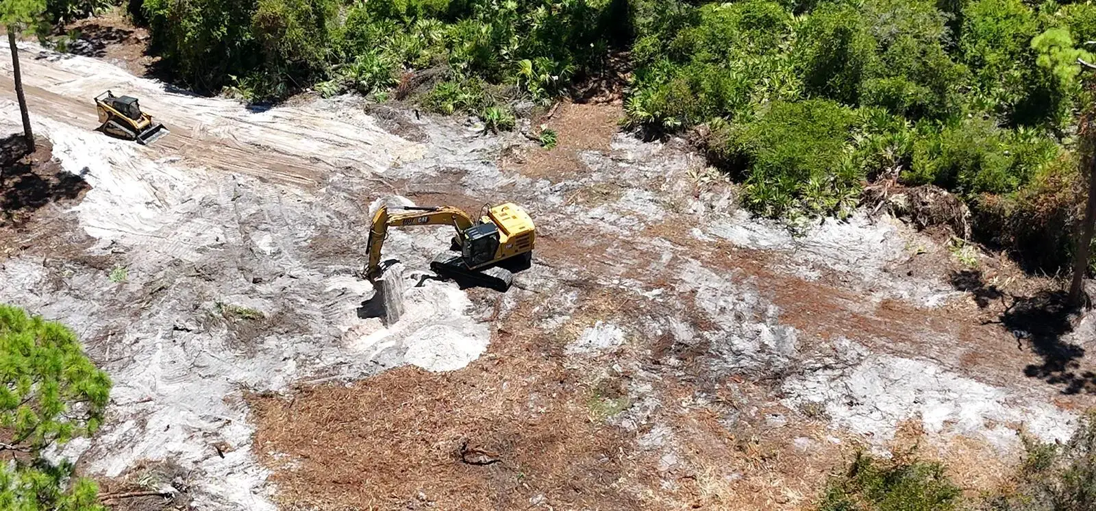 Excavator moving fill on a driveway cut in Lehigh Acres, Florida