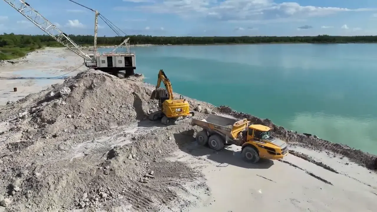 Dragline and excavator loading an articulated truck on white limestone during a lake excavation in Bonita Springs, Florida