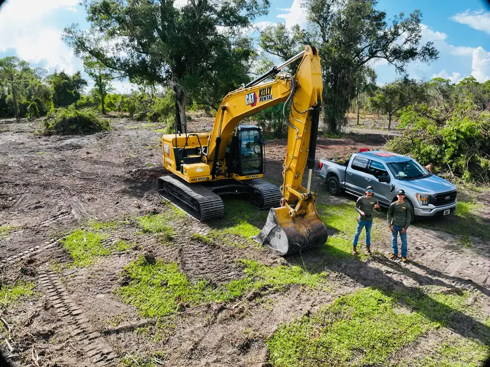 Site preparation crew and excavator shaping a building pad — Hector Tractor, Bonita Springs, FL